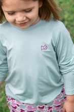 Load image into Gallery viewer, Meet the ultimate outdoor tee for adventurous girls and peace-of-mind moms! Girls&#39; Pro Performance Long Sleeve T-shirt in Blue Surf with Pink Camo&nbsp;is made to move, protect, and play all day. Featuring our signature PRODOH logo with a pink camo border and &quot;An Outdoor Tradition&quot;, this shirt adds a stylish twist to the functional favorite.
