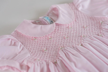 Load image into Gallery viewer, An utterly precious little girl&#39;s dress from Feltman Brothers! Scalloped stitching lines both the collar and puffed sleeves of this sweet looking dress, making it a perfect choice for your little darling. The smocking is covered in a beautiful diamond stitching and is embellished with hand embroidered clover flowers with a delicate pearl in the center of each. A zigzag design ends off the smocked bodice, and then continues into classy pleats down the length of the dress. Ties in the back with a lovely bow f
