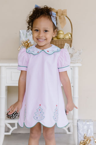 Celebrate the season in style with the Girl's Pink Christmas Tree Kendall Dress by Zuccini Kids. This charming light pink A-line dress features a delicate white peter pan collar with scalloped edges and intricate embroidery. Festive Christmas trees embroidered along the scalloped hem add a whimsical holiday touch, perfect for special occasions and holiday photos. 