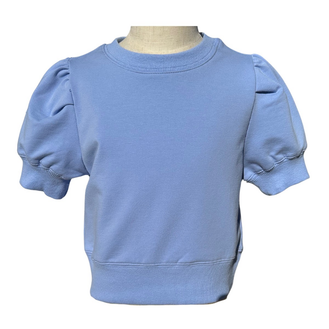 The Riley Sweatshirt in Cornflower is a charming short-sleeve top featuring stylish puffed shoulders that add a playful touch to any tween girl's wardrobe. Crafted from comfortable sweatshirt material, it offers a cozy feel perfect for crisp fall days. Pair it effortlessly with tiered pleat skirts to create a fashionable, coordinated look your child will love wearing throughout the season.