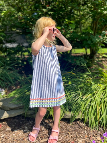 The Girls Libby Dress with Rainbow Ric Rac from Duffield Lane is a chic and timeless piece, perfect for any little fashionista. Featuring a classic navy and white stripe design, with eye-catching rainbow ric rac accents on the hem and shoulders. This dress will add a touch of color and fun to any wardrobe.
