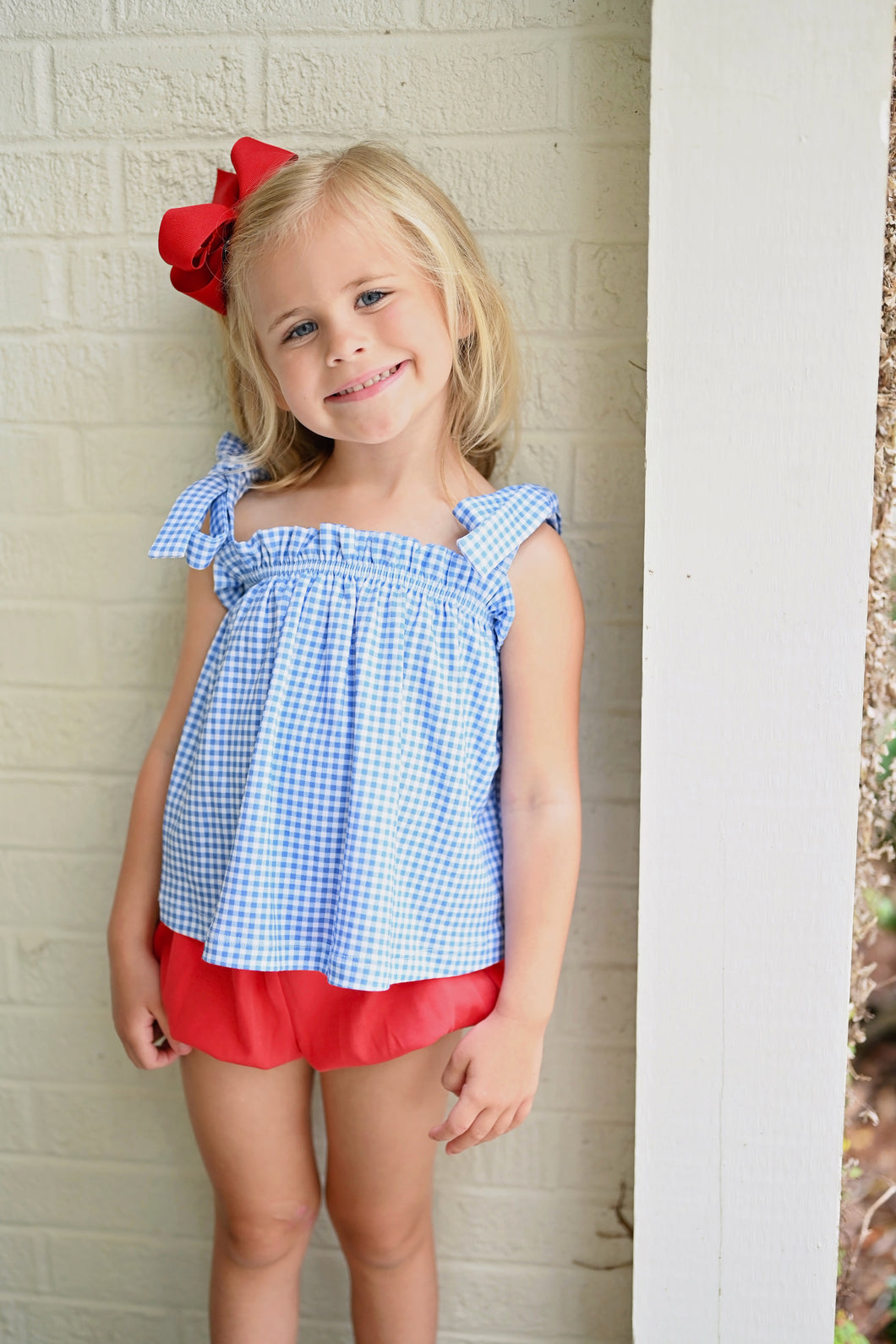 Elevate your little girl's wardrobe with this charming Blue Gingham Knit Tie Top from James & Lottie. The timeless blue and white gingham pattern creates an irresistible look, while the playful tie straps add a touch of whimsy. This versatile piece transitions effortlessly from playground to parties, and creates a perfect patriotic ensemble when paired with the red Kinley Ruffle Shorts. A must-have addition that combines comfort and classic style for your fashion-forward little one.