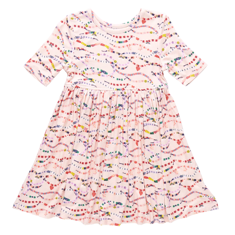In our Friendship Bracelet Era! This exclusive new print from Pink Chicken, inspired by your favorite superstar, is a must-have for your stylish kiddos. This nostalgic print highlights positive messaging such as kindness, happiness and friendship - and is the perfect dress for class, a playdate, but most of all, your next concert. The classic Steph Dress silhouette is loved for its super swingy fully gathered skirt and skinny sleeve that hits right above the elbow. The soft and silky bamboo fabric is best k