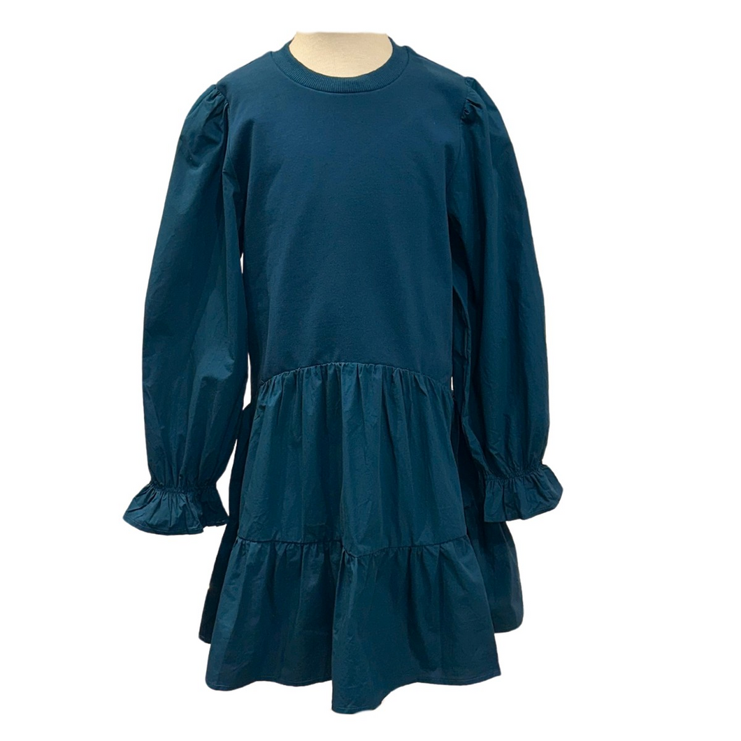 The Cece Dress in Dark Cerulean by Pleat combines comfort and style with its tiered skirt and long sleeves gathered at the wrists. Perfectly suited for fall events, this dress offers a flattering silhouette and effortless elegance, making it an ideal choice for your little one’s seasonal wardrobe.